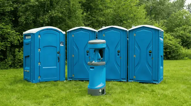 Four blue portable toilets and a matching hand washing station on grass near trees, a common sight at local outdoor events in Louisville, KY